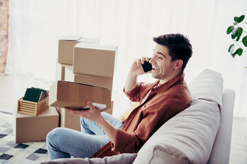 Young man enjoying relocation and unpacking in a stylish living room while conversing on his phone