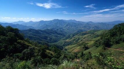 Obraz premium Lush green hills stretch across the horizon in a stunning mountainous landscape. The vibrant valleys create a serene atmosphere, framed by a bright blue sky with wispy clouds.