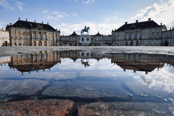 Blick auf die Reiterstatue von Friedrich V. und eine Spiegelung in einer Wasserpfütze auf dem Platz vor Schloß Amalienburg in Kopenhagen