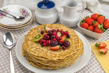 Desayuno con crepes servidos con kiwi, fresas y frutos rojos.