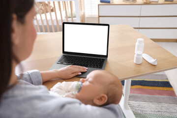 Telehealth. Mother with her baby having online consultation with doctor at table indoors, closeup
