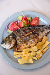 Pescado frito con ensalada y patatas fritas en Grecia