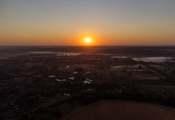 Aerial view of sunrise over a rural Ukrainian village with farmland, fields, and countryside homes in morning light