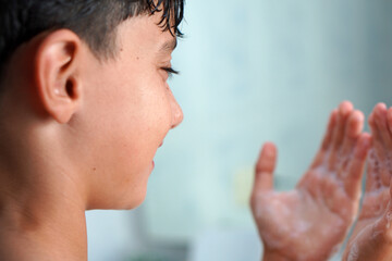Fototapeta premium Hygiene in children and adolescents skincare. Preteen boy washing his face with soap and water.