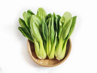 Top view of Fresh green vegetables mustard. Bok choy or pak choi or pakcoy (Brassica rapa subsp. chinensis) in bamboo bowl. Isolated on white background with copy space.