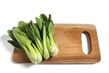Fresh bok choy or pak choi or pakcoy (Brassica rapa subsp. chinensis) vegetables on the wooden cutting board. Isolated on white background with copy space.