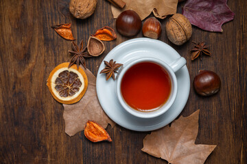 Aerial view of a cup of tea on a table with nuts and autumn leaves, horizontal, with copy space