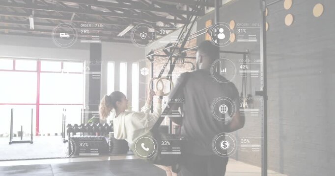 Client grabbing rings while performing ring rows for strength with trainer observing data updating