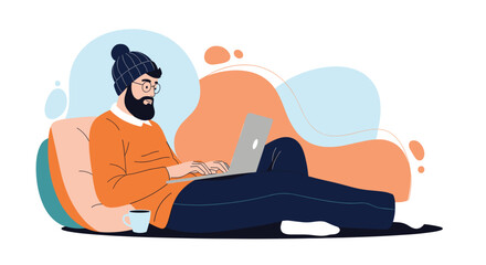 Fototapeta premium A man with a beard wearing a beanie and an orange sweater sits on a couch and works on a laptop with a cup of coffee nearby.