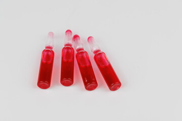 Intense red vitamin B12 ampoules displayed on white surface, representing supplements and health.