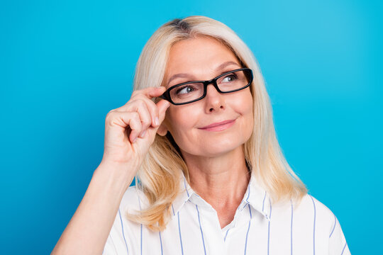 Thoughtful mature businesswoman portrait in blue studio featuring confident executive style and professional elegance