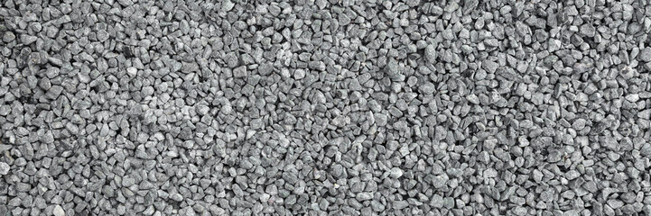 Light gray granite gravel road background. Closeup. Wide banner. Top down view.