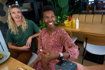 Woman paying contactless with smartwatch in restaurant