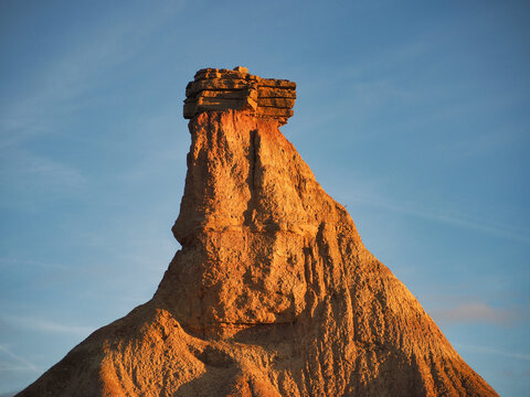 Dramatic eroded desert rock formation at sunset - The distinctive Castil de Tierra formation in Bardenas Reales, Spain, under golden hour light and a clear blue sky.