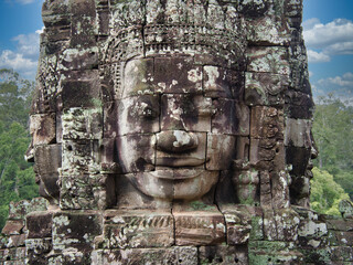 Khmer Smiling Stone Face - A close-up of a weathered, smiling stone face carving on a historic temple at Angkor, with detailed features and textures.
