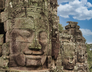 Khmer Smiling Stone Face - A close-up of a weathered, smiling stone face carving on a historic temple at Angkor, with detailed features and textures.