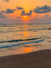 Sunset Over Ocean Waves on Sandy Beach
