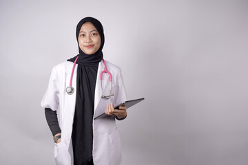 Asian Muslim doctor holding medical records, putting his hands in his lab coat and carrying a...