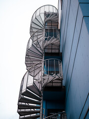 Round stairway up on the side of a blue building