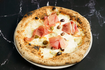 Artisan pizza with prosciutto and olives