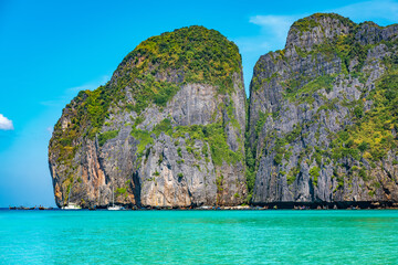 Towering limestone karsts creating the iconic entrance to Maya Bay, with turquoise water and longtail boats dotting the Andaman Sea, a serene tropical island landscape in Krabi, Thailand