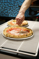 Chef sprinkling cheese over traditional pizza