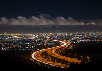 Obraz premium Cityscape at Night with Overpass and Distant Snowy Mountain Peak Illumination