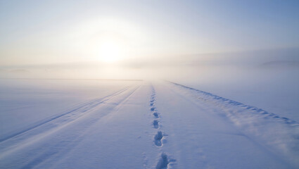 Snow trail with footprints in open field