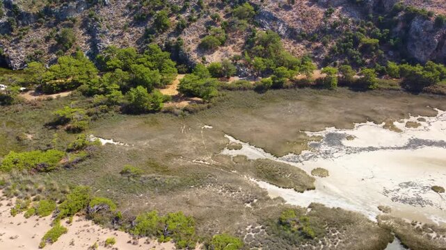 An aerial panoramic view captures the stunning natural beauty of Iztuzu Beach near Dalyan, Turkey, showcasing the narrow sandy spit separating the freshwater Dalyan River delta from the Mediterranean 