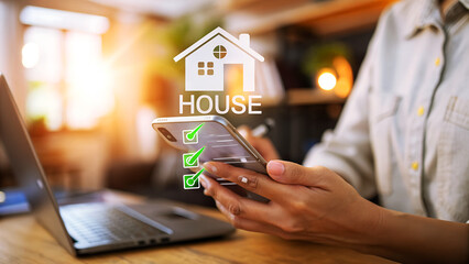 Woman using smartphone to search for a new house and check the list of features she wants in her new home in a bright sunny room