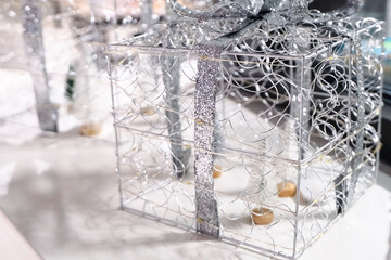 A decorative silver wire gift box with glitter ribbon and festive lights, capturing the sparkle and elegance of holiday season celebrations.