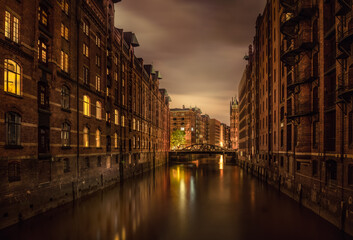 Naklejka premium Historic Speicherstadt Warehouse District in Hamburg at Night with Illuminated Canals and Reflections in Calm Water