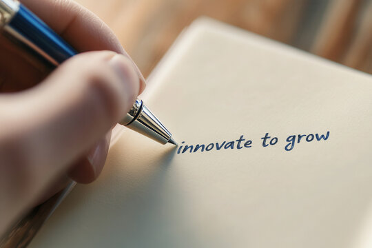 Close up of a human hand holding a pen, writing the motivational business phrase innovate to grow on a simple notebook, symbolizing development and creative thinking