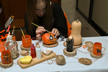 A girl paints a pumpkin for Halloween