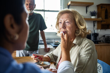 Caregiver helping a senior woman while eating at home