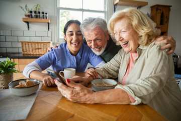Senior couple and caregiver using a smartphone at home