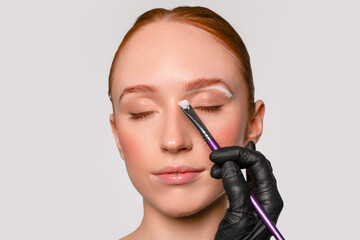 Obraz premium A woman is undergoing an eyebrow bleaching procedure at a beauty salon, keeping her eyes gently closed