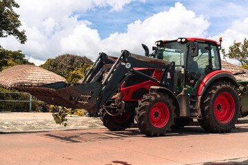 Red tractor with front loader parked outdoors, Jeju Island, South Korea
