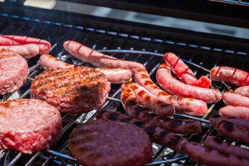Burgers and sausages already cooked on the barbecue grill. You know they are already cooked because they have the grill marks on them.