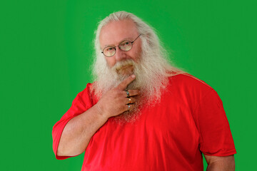 Man dressed as Santa Claus poses thoughtfully against a green screen background, wearing glasses and a red shirt