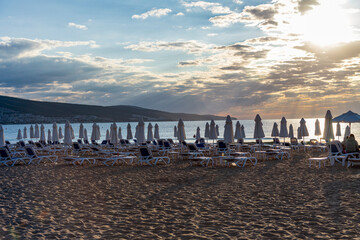 Wooden sun loungers arranged on a sandy beach by the calm sea under a clear blue sky. The relaxing...