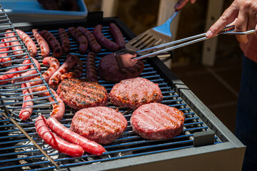 Neighbor using kitchen utensils to turn the meat over and cook it on both sides. He is doing it on his barbecue outside his house.