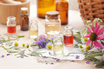Variety of aroma essential oils in glass bottles with aromatic flowers on natural background, copy space, natural cosmetic, skin treatment, aromatherapy and menopause health concept