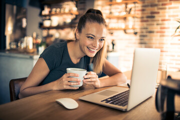 Woman enjoying coffee while using laptop