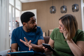 Worried Interracial Couple Struggling with Financial Problems at Home, Concerned About Rent Prices,...