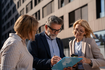 Diverse business people enjoying coffee break and chatting outdoors in corporate business district	