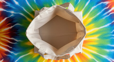 Vibrant tie-dye backdrop enhances empty reusable canvas tote bag for eco-conscious style