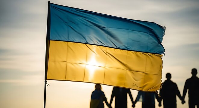 Ukrainian flag waving with people holding hands at sunset.