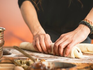 A person carefully rolls out dough on a floured board, preparing to bake traditional sweet bread. The warm light suggests it's a festive preparation for a holiday