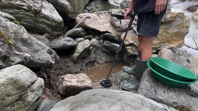 Outdoor adventures on river. Gold panning in a mountain creek, search for gold in summer. Man with boots is looking for gold with a metal detector